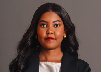 Nangula Iithete1 - The Brief | Namibia's Leading Business & Financial News Portrait of a woman with long black hair, wearing a black blazer and white top, looking at the camera on a gray studio backdrop
