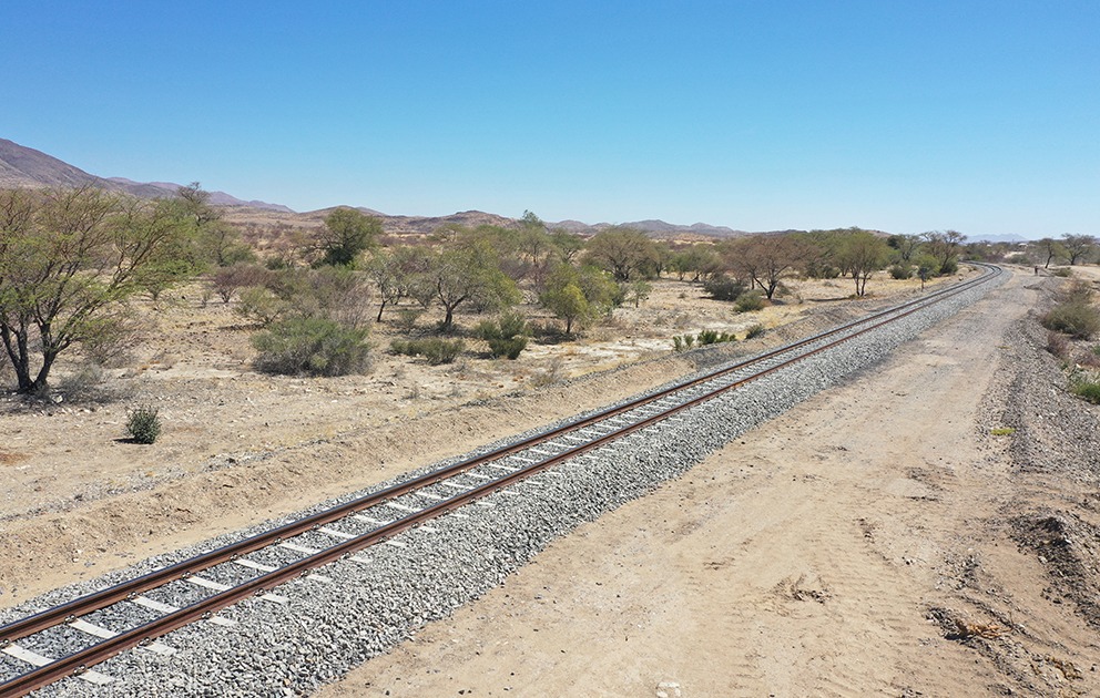 RAILWAY - The Brief | Namibia's Leading Business & Financial News Desert landscape with a single set of railroad tracks curving into the distance under a clear blue sky.