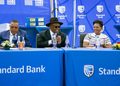 WhatsApp Image 2026-08-24 at 101407 PM - The Brief | Namibia's Leading Business & Financial News Five professionals sit at a long blue Standard Bank table during a formal event, with water bottles and small floral arrangements in front of them at a branded backdrop.