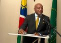NGURARE09 - The Brief | Namibia's Leading Business & Financial News A man in a dark suit giving a speech at a podium with two flags in the background.