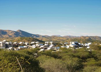 WhatsApp Image 2026-09-02 at 85121 AM - The Brief | Namibia's Leading Business & Financial News Cluster of white-roofed houses nestled in a desert landscape with hills under a blue sky.