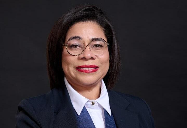 FIC Zenobia 1 1 - The Brief | Namibia's Leading Business & Financial News Professional portrait of a woman with short dark hair and glasses, wearing a navy blazer and white shirt against a dark backdrop.