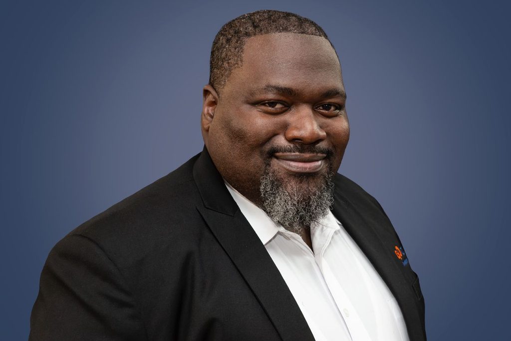 WhatsApp Image 2026-09-03 at 152429 - The Brief | Namibia's Leading Business & Financial News Professional headshot of a smiling Black man in a black blazer and white shirt against a blue gradient background.