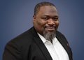 WhatsApp Image 2026-09-03 at 152429 - The Brief | Namibia's Leading Business & Financial News Professional headshot of a smiling Black man in a black blazer and white shirt against a blue gradient background.