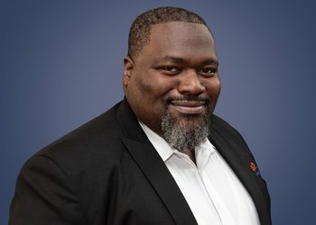 WhatsApp Image 2026-09-03 at 152429 - The Brief | Namibia's Leading Business & Financial News Professional headshot of a smiling Black man in a black blazer and white shirt against a blue gradient background.