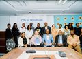 Group of men and women in business attire posing for a photo in a conference room; backdrop reads 'City of Windhoek'.