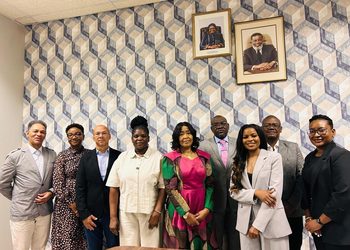 WhatsApp Image 2026-09-10 at 54046 PM - The Brief | Namibia's Leading Business & Financial News Eight professionals standing together in a conference room with a geometric blue wallpaper and framed portraits above them.