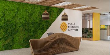 Reception lobby with a green vertical moss wall, curved wooden bench, and World Resources Institute logo on a white wall nearby