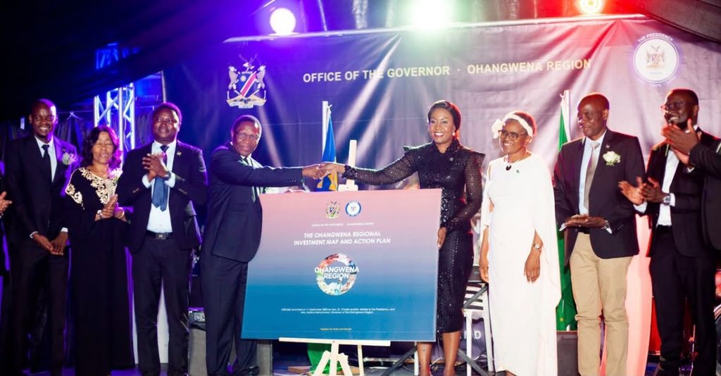 Officials on stage shake hands over a poster titled Ohangwena Region Investment Map and Action Plan at a formal ceremony