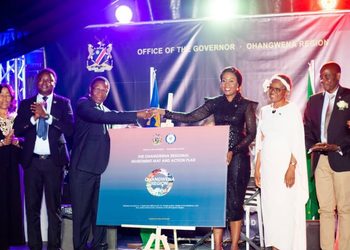 Officials on stage shake hands over a poster titled Ohangwena Region Investment Map and Action Plan at a formal ceremony