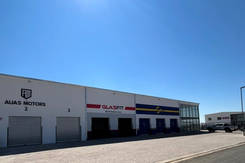 GLASFIT - The Brief | Namibia's Leading Business & Financial News White industrial complex with three garage bays and signs for AUAS MOTORS and GLASFIT under a clear blue sky.
