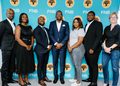Seven professionals posing for a group photo in front of a teal FNB banner, smiling and dressed in business attire.