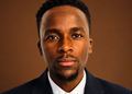 Nghuulili Martin Image - The Brief | Namibia's Leading Business & Financial News Close-up portrait of a Black man in a navy suit and white shirt, facing the camera against a brown studio backdrop.