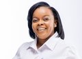 Smiling woman with black hair in a white shirt against a pale background.