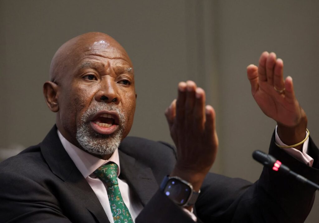 Close-up of a man in a dark suit speaking passionately, hands raised in a gesturing motion.