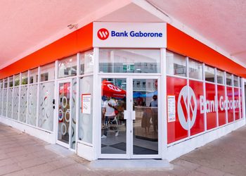 BANK GABORONE1 - The Brief | Namibia's Leading Business & Financial News Exterior view of a Bank Gaborone branch with a glass storefront and bright red branding above the entrance, showing the logo and signage clearly.