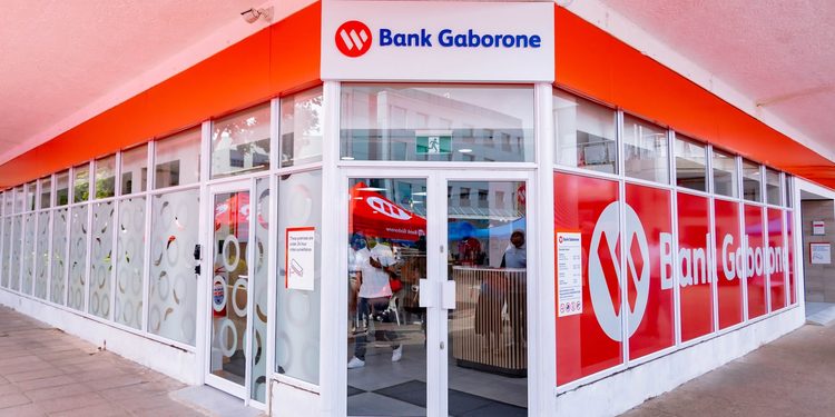 Exterior view of a Bank Gaborone branch with a glass storefront and bright red branding above the entrance, showing the logo and signage clearly.