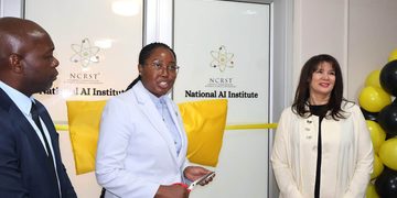 Three professionals at a ribbon-cutting ceremony for the National AI Institute, with yellow cushions and balloons nearby.