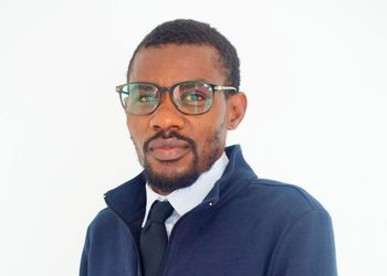 NOAH JONAS - The Brief | Namibia's Leading Business & Financial News Professional headshot: man with glasses, white shirt, black tie, and navy jacket facing the camera against a white background.