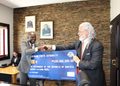 WhatsApp Image 2026-09-30 at 94805 AM - The Brief | Namibia's Leading Business & Financial News Two men in suits shake hands while presenting a blue ceremonial cheque from the Namibian Ports Authority in an office with a stone wall and framed portraits.