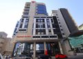 Modern office building with a striped glass facade, curved balconies on the left, and a red 'Capricorn-on-Main' sign at ground level.