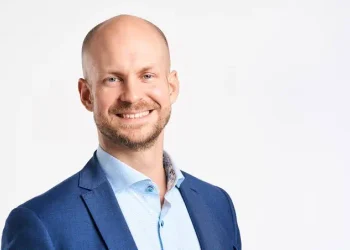 Smiling man in a blue blazer and light blue shirt against a white studio background (professional headshot).