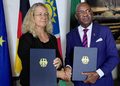 WhatsApp Image 2026-10-06 at 113001 AM - The Brief | Namibia's Leading Business & Financial News Two professionals shake hands while each holds a navy folder with a gold emblem, standing before national flags in a formal setting.