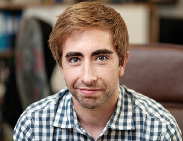 Robert McGregor - The Brief | Namibia's Leading Business & Financial News Young man with light brown hair and stubble, wearing a blue-and-white checkered shirt, looking at the camera in an office.