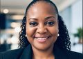 Smiling Black woman in a black blazer with pearl earrings, in an office setting (close-up portrait).