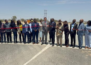 WhatsApp Image 2026-10-09 at 110949 AM - The Brief | Namibia's Leading Business & Financial News Group of officials and community members standing on a highway, cutting a red ribbon to open a new road.