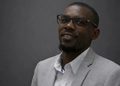 NOAH - The Brief | Namibia's Leading Business & Financial News Head-and-shoulders portrait of a man in a light gray suit and white shirt, wearing glasses, smiling slightly.
