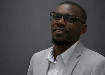 NOAH - The Brief | Namibia's Leading Business & Financial News Head-and-shoulders portrait of a man in a light gray suit and white shirt, wearing glasses, smiling slightly.