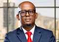 Tsaone Raboloko - The Brief | Namibia's Leading Business & Financial News Portrait of a bald man in a navy suit and red tie, wearing black-ramed glasses, looking at the camera in an office setting