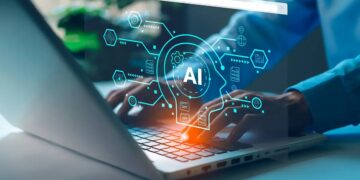 Hands typing on a laptop with a glowing blue AI holographic network overlay above the keyboard.