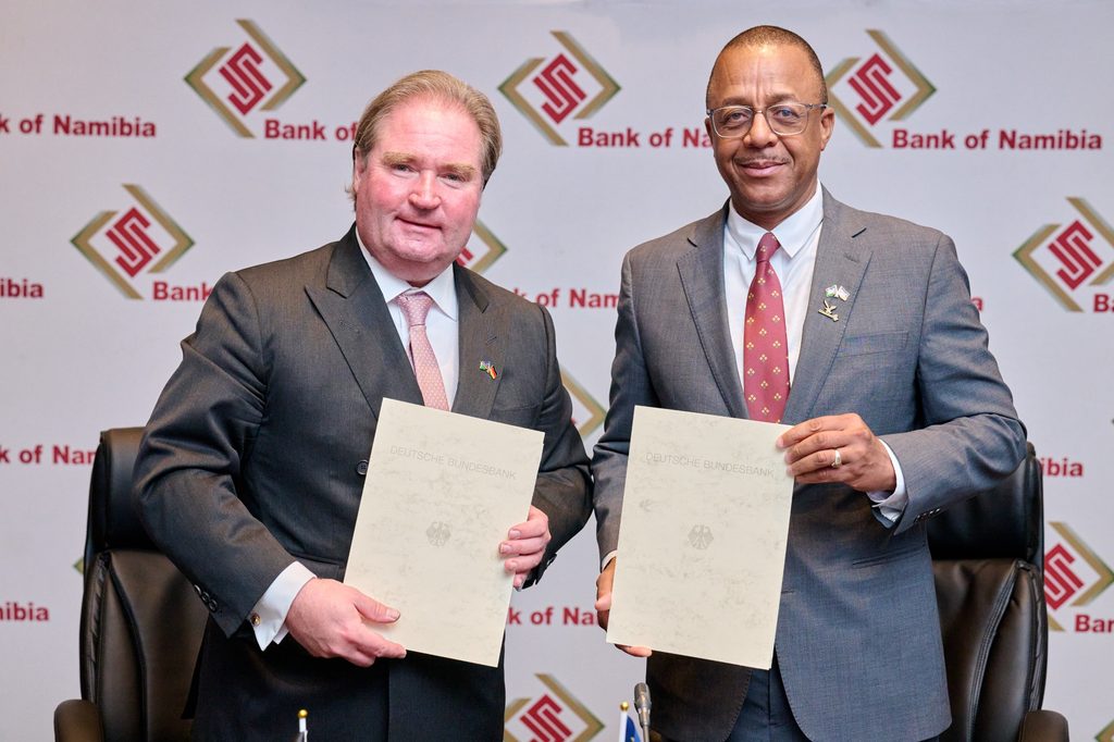 WhatsApp Image 2026-10-13 at 45223 PM - The Brief | Namibia's Leading Business & Financial News Two businessmen in suits pose with documents at a Bank of Namibia event backdrop.