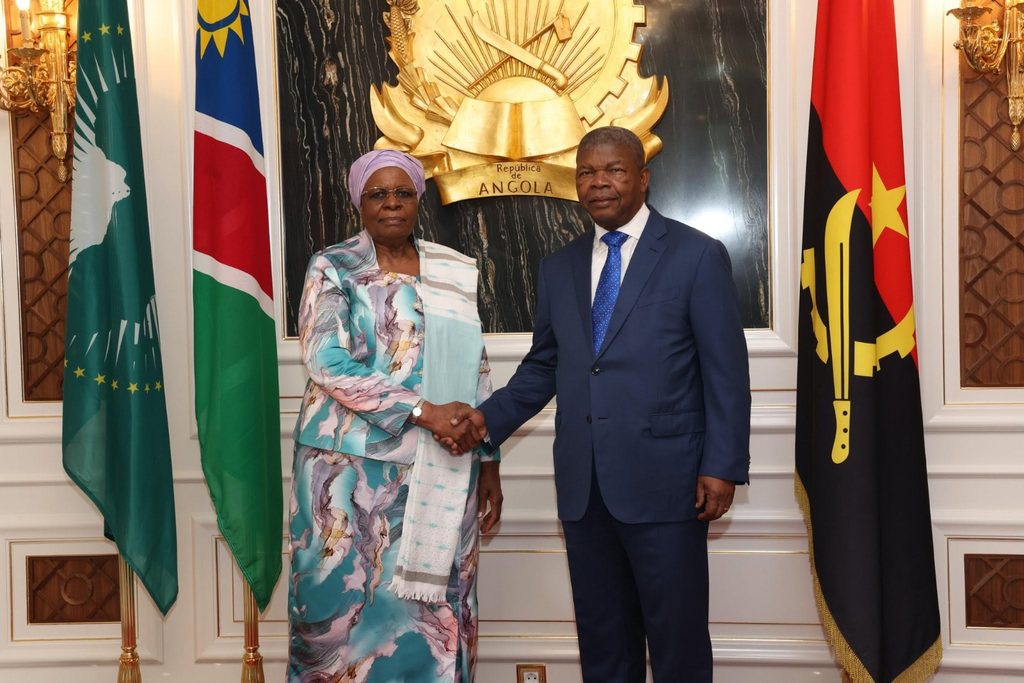 WhatsApp Image 2026-10-14 at 55106 PM - The Brief | Namibia's Leading Business & Financial News Two officials shake hands in a formal government setting, with a gold emblem behind them and multiple national flags on either side.