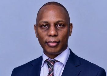 Andrew Njeru - The Brief | Namibia's Leading Business & Financial News Professional headshot of a man in a navy suit and plaid tie against a light blue backdrop, neutral expression.