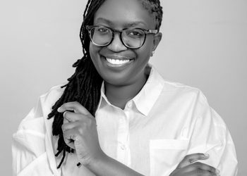 Luise Mwanyangapo - The Brief | Namibia's Leading Business & Financial News Smiling woman with glasses and braids in a white button-down shirt, facing the camera in a portrait.