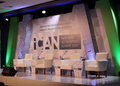 ICAN - The Brief | Namibia's Leading Business & Financial News Stage setup for ICAN National Accounting Summit 2024 with five white chairs, microphones, and water bottles on a patterned backdrop.