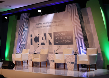 Stage setup for ICAN National Accounting Summit 2024 with five white chairs, microphones, and water bottles on a patterned backdrop.