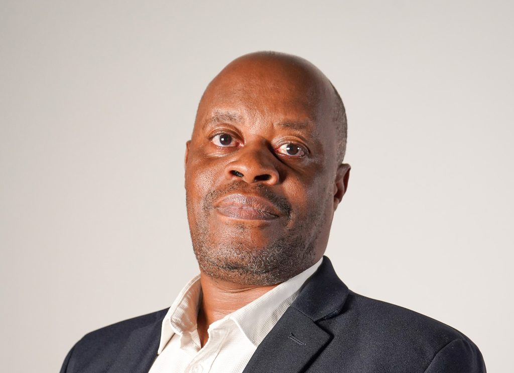 Portrait of a middle-aged man in a dark blazer and white shirt looking at the camera.