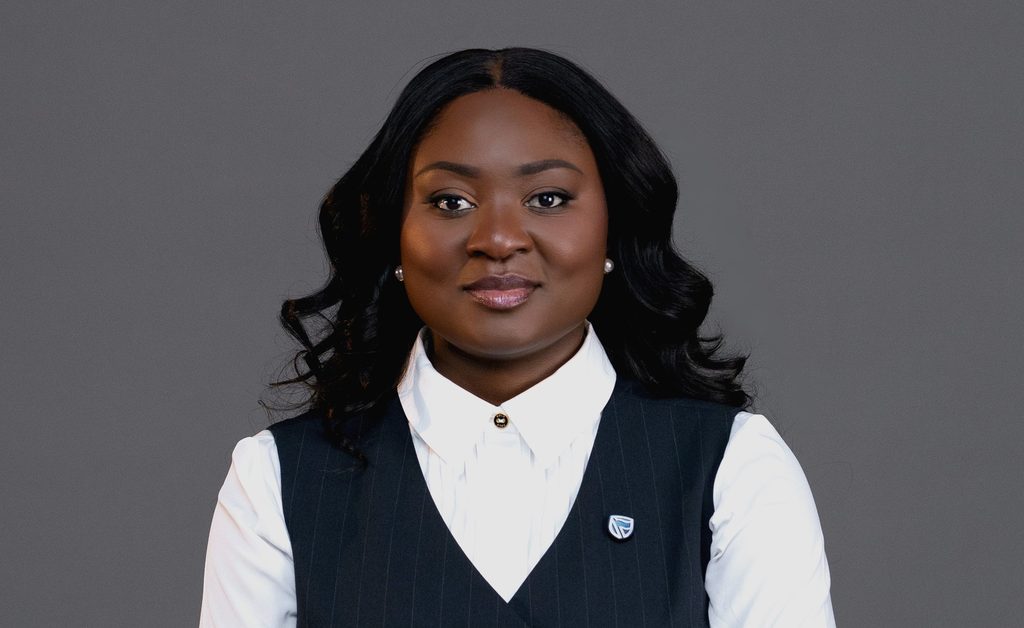 Professional woman in a white collared shirt and pinstripe vest, facing the camera against a gray background.