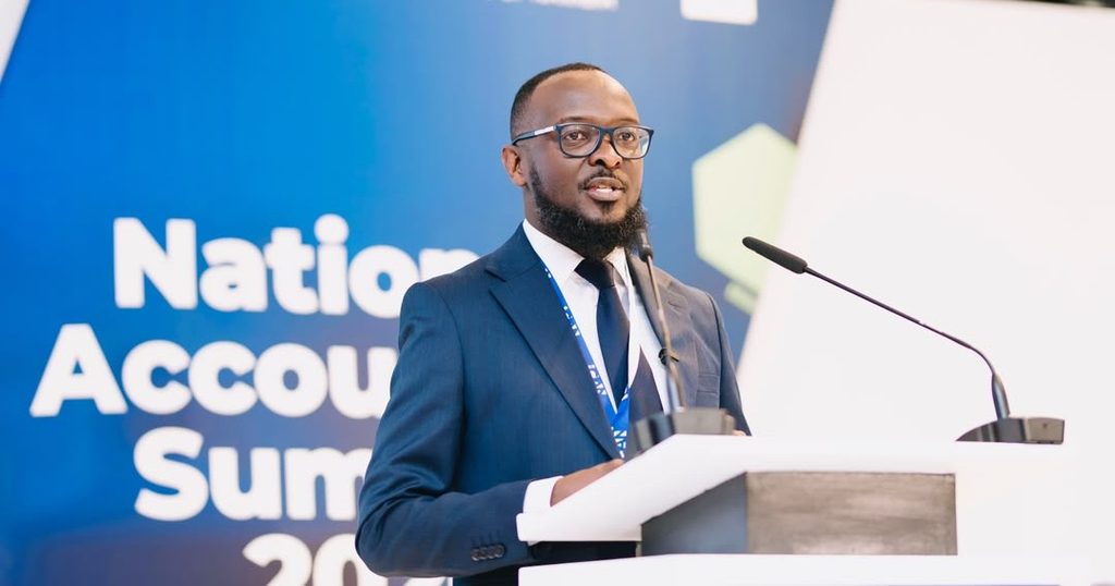 WhatsApp Image 2026-10-23 at 121601 PM - The Brief | Namibia's Leading Business & Financial News Man in a blue suit and glasses speaks at a podium during a National Accounts Summit, with a blue backdrop behind him.