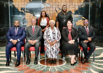 WhatsApp Image 2026-10-23 at 52213 PM - The Brief | Namibia's Leading Business & Financial News Group of seven professionals in formal attire posing in a marble lobby with a world map backdrop.
