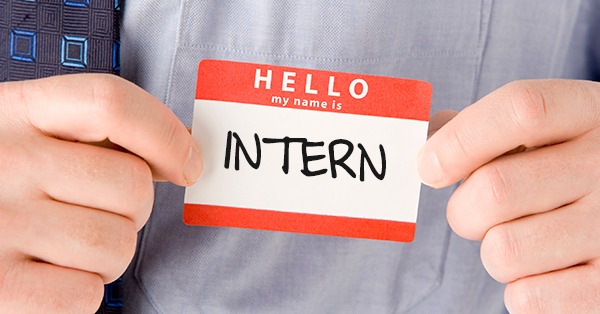 Name badge reading 'Hello, my name is INTERN' being shown by a person in a shirt and tie.