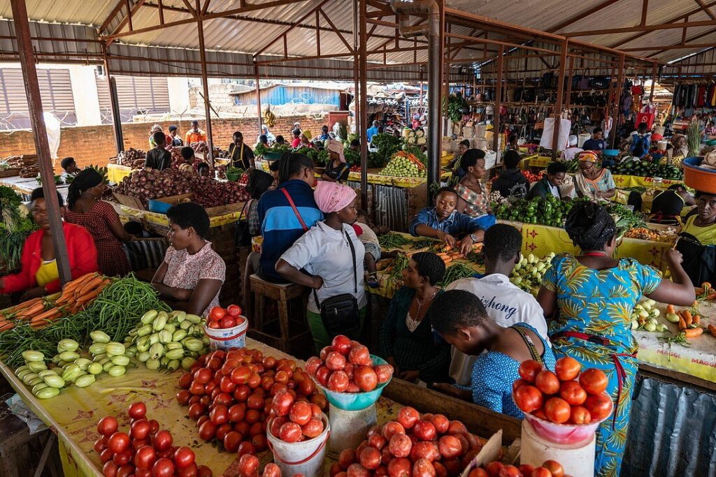INFORMAL MARKETS - The Brief | Namibia's Leading Business & Financial News Bustling open-air market with stalls of tomatoes, peppers, and greens as shoppers browse and interact under a corrugated roof.