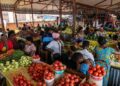 INFORMAL MARKETS - The Brief | Namibia's Leading Business & Financial News Bustling open-air market with stalls of tomatoes, peppers, and greens as shoppers browse and interact under a corrugated roof.