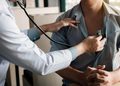 Doctor uses a stethoscope to listen to a patient's chest during a checkup.