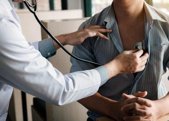 Doctor uses a stethoscope to listen to a patient's chest during a checkup.