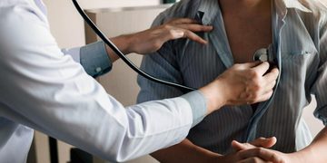 Doctor uses a stethoscope to listen to a patient's chest during a checkup.